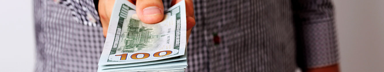 Man holding out stack of 100 dollar bills.