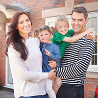 Parents with son and daughter outside their house.