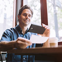 Man taking photo of check at table.