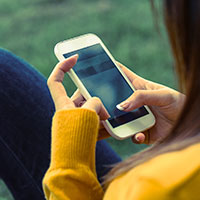 Woman holding phone outdoors.