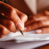 Woman writing entry in checkbook.