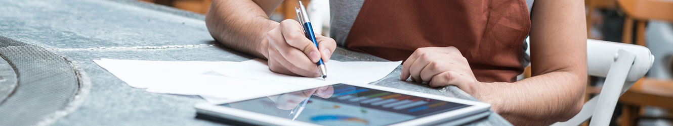 Male employee writing with tablet next to him.